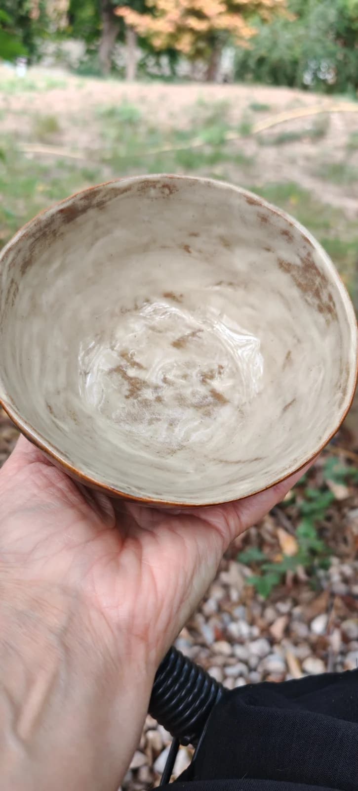 Intérieur d'un bol artisanal en céramique émaillée aux nuances claires et beige moucheté.